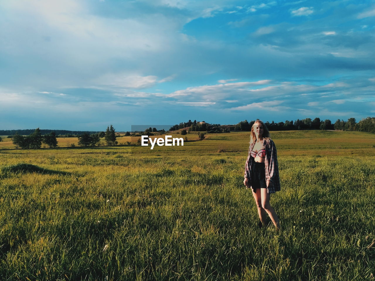 Fashionable young woman standing on grassy field against sky