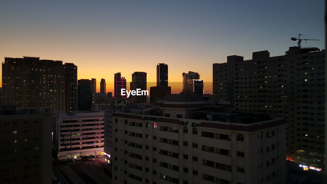 MODERN BUILDINGS IN CITY AGAINST SKY AT SUNSET