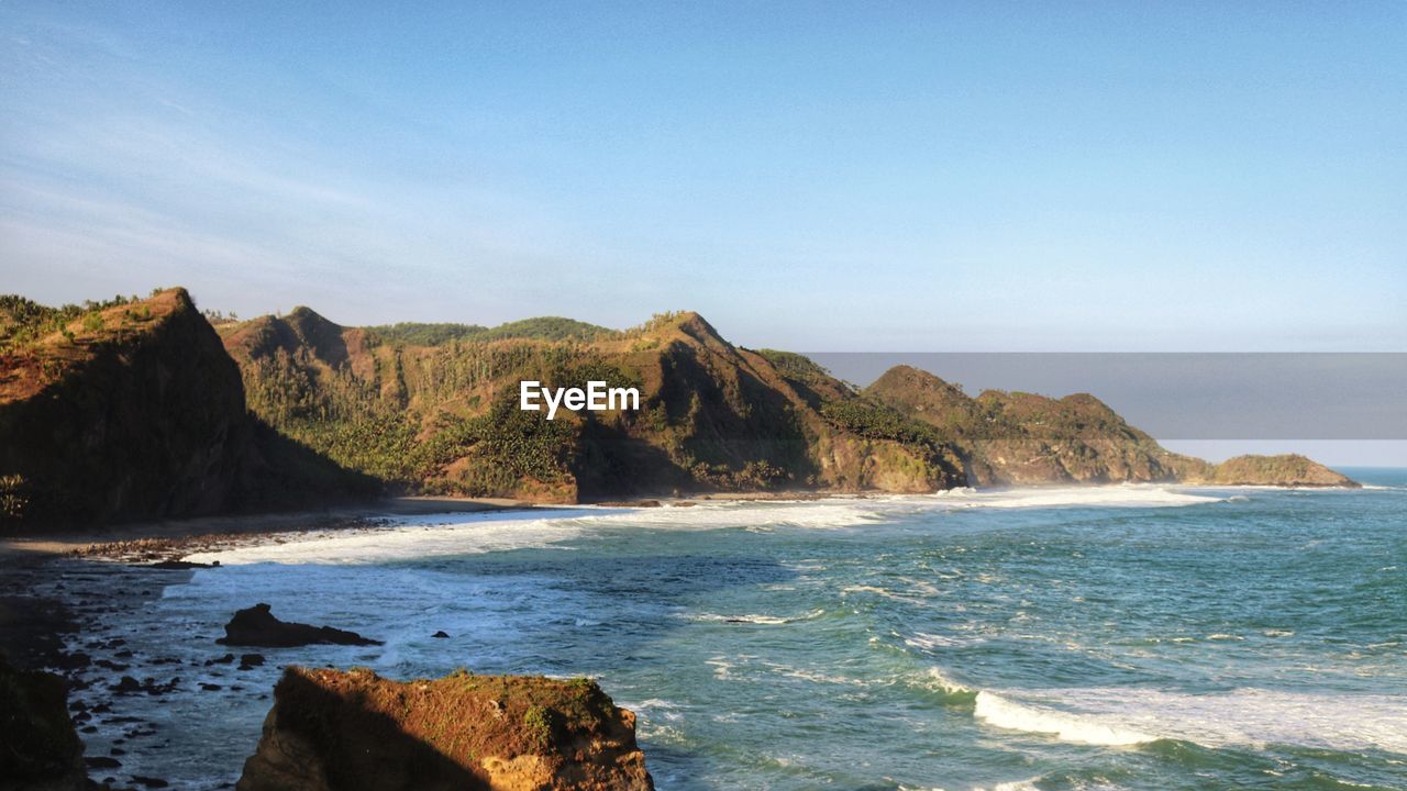 Scenic view of rocks on beach against sky