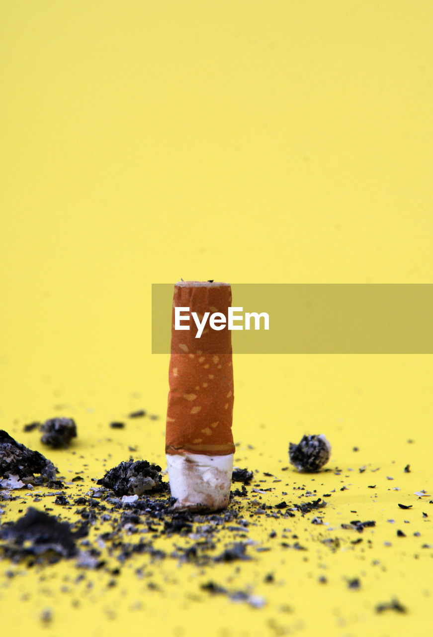 Cigarette butt against yellow background