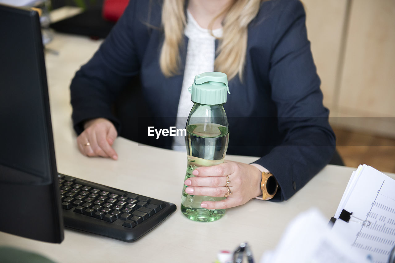 Close up of business woman hands holding plastic bottle mineral water on a desk at the office