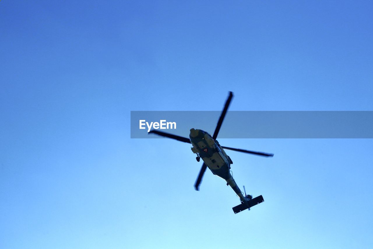 Low angle view of helicopter against clear blue sky