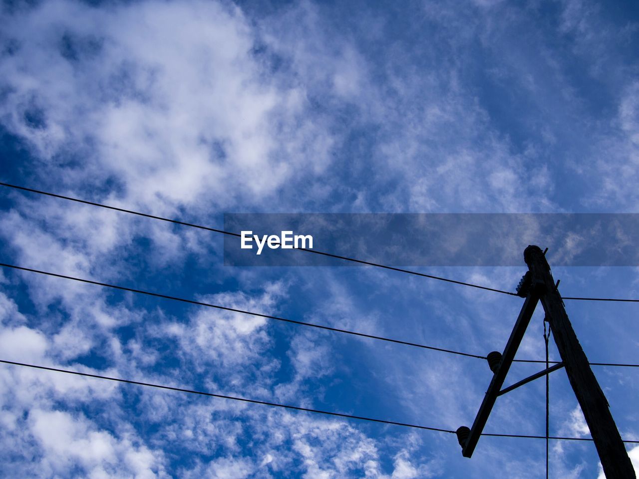 Upward view of power lines against sky
