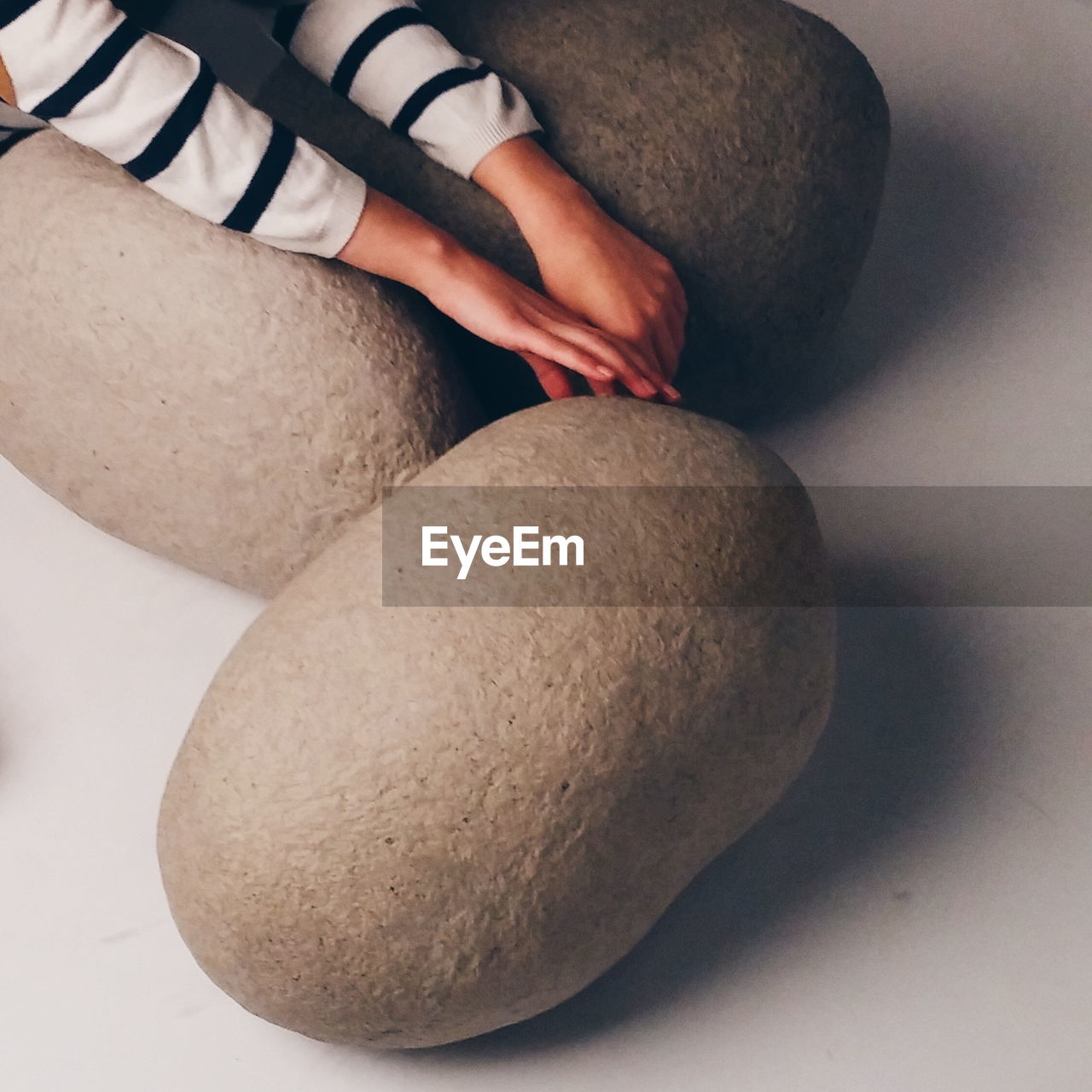 Cropped image of woman hands with stones on white background