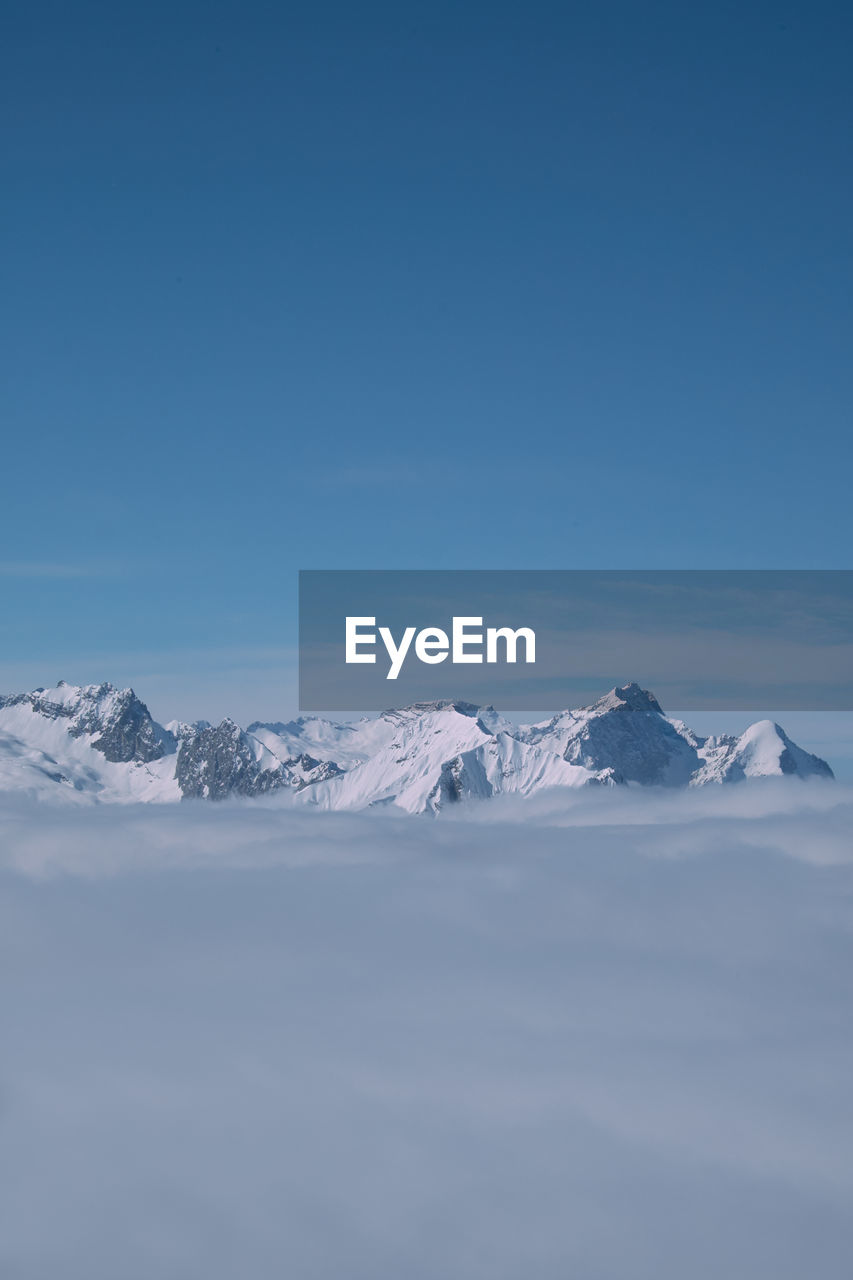 Scenic view of snowcapped mountains against blue sky