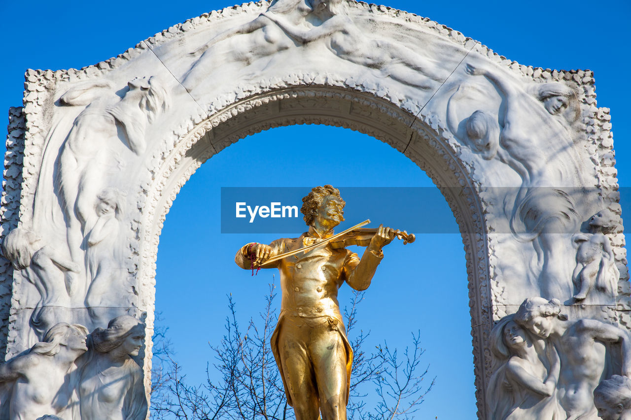 Low angle view of angel statue against blue sky