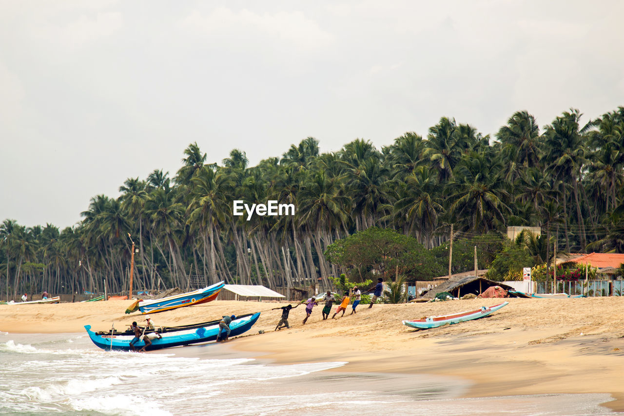  local fishermen in the morning pulling a boat to shore after fishing nets off the coast 