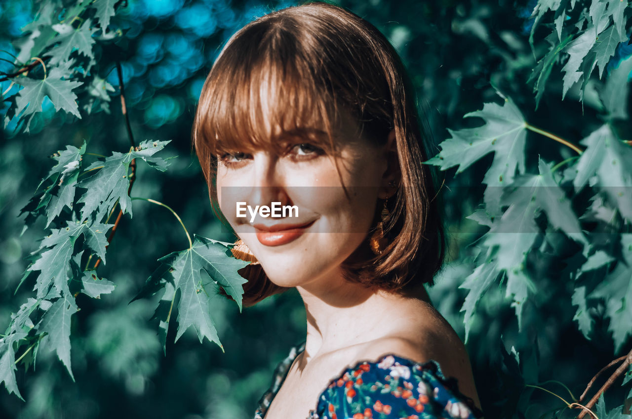 PORTRAIT OF BEAUTIFUL YOUNG WOMAN WITH LEAVES IN PLANT