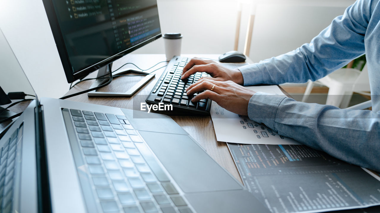 Cropped hand of businessman using computer on table