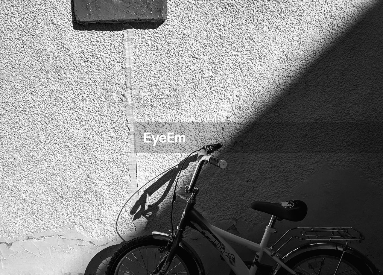 SHADOW OF BICYCLE LEANING ON WALL