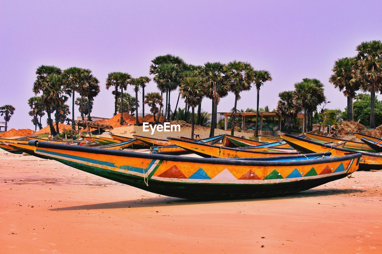 Boats moored on beach against clear sky