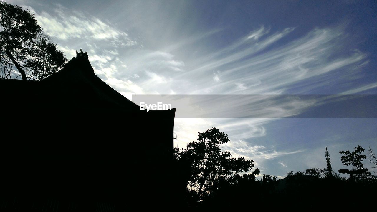 Low angle view of dramatic sky over silhouette buildings