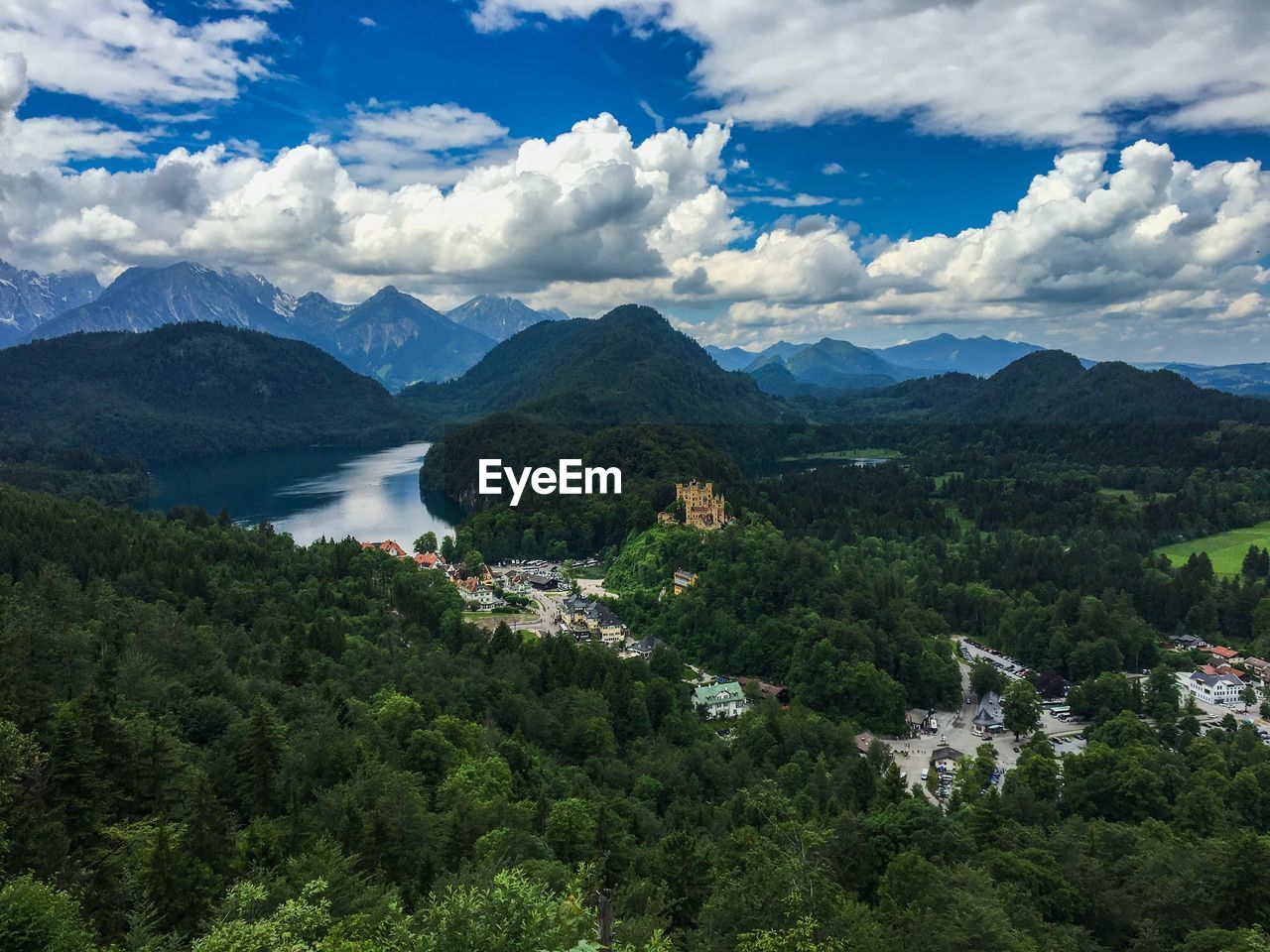 Scenic view of hohenschwangau castle by alpsee amidst trees against sky