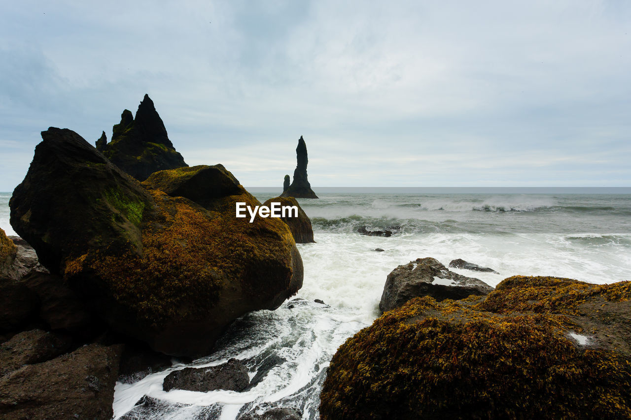 ROCK FORMATIONS ON BEACH AGAINST SKY