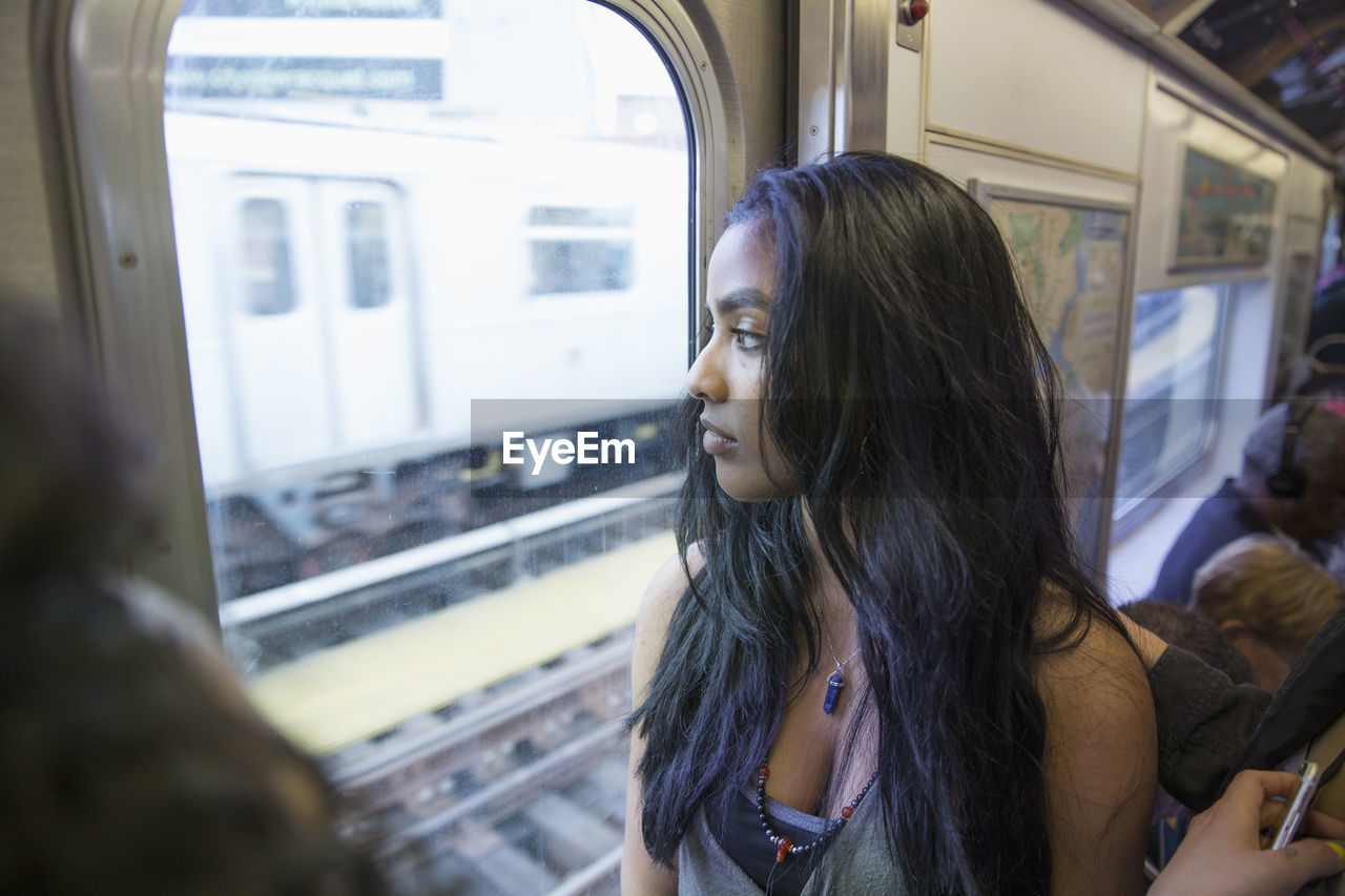 Young woman looking out the window of a train in queens, new york
