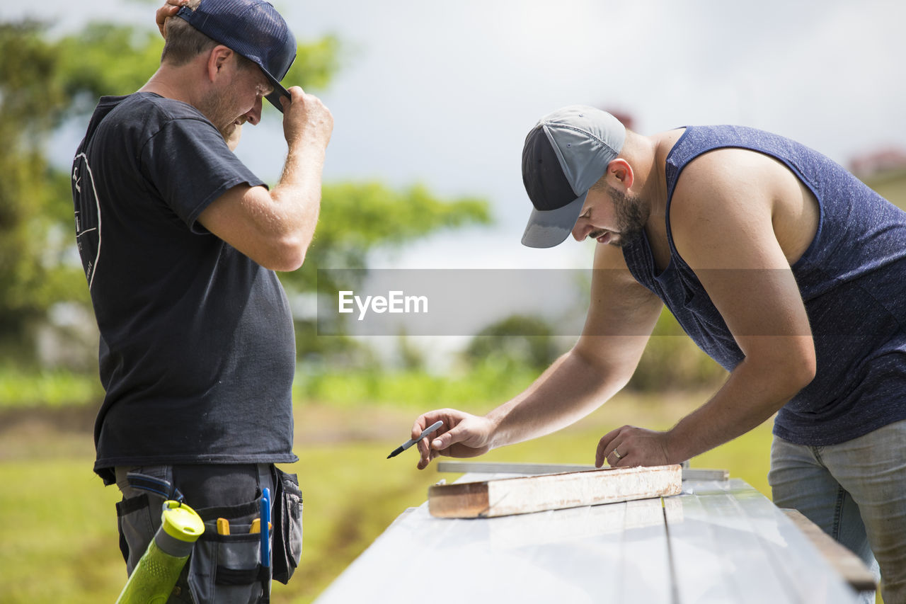 Two men measuring brackets for solar panel installation.