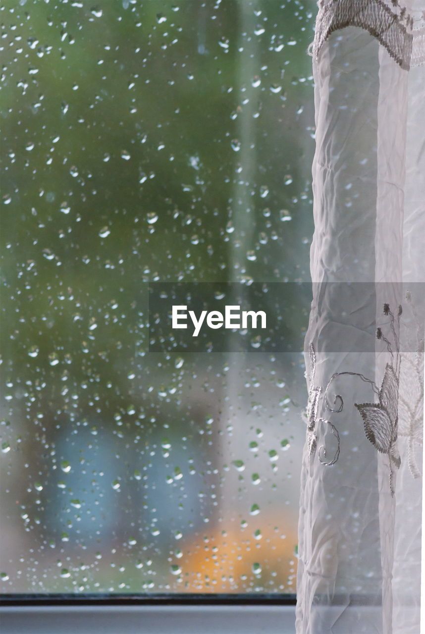 CLOSE-UP OF RAINDROPS ON GLASS WINDOW