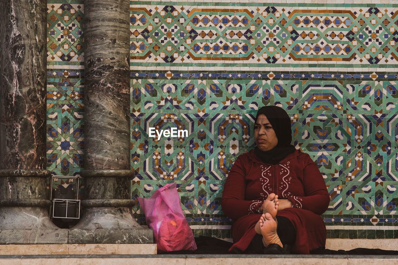 FULL LENGTH OF WOMAN SITTING ON CROSS