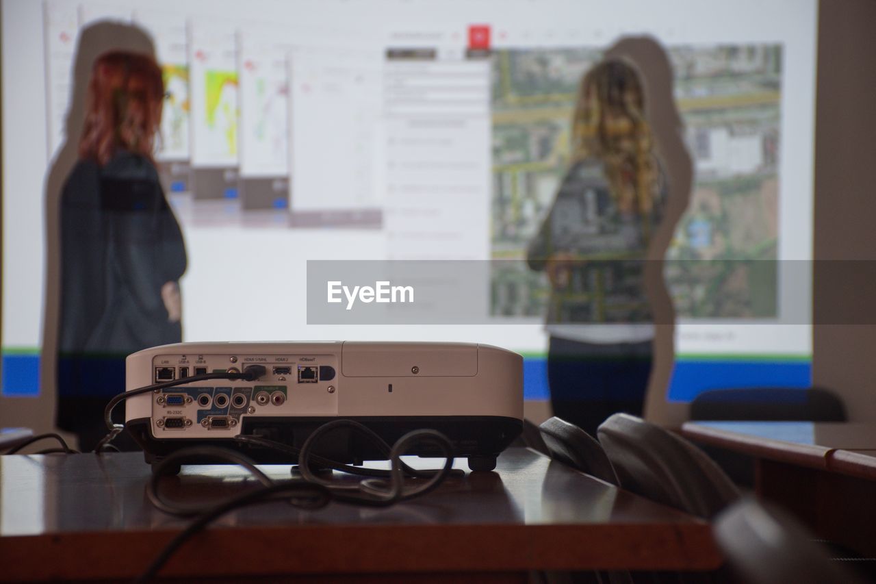 Colleagues standing by projection screen on wall during meeting