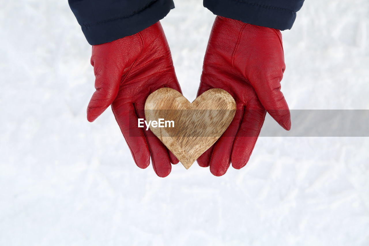 Low section of woman holding heart shape in winter