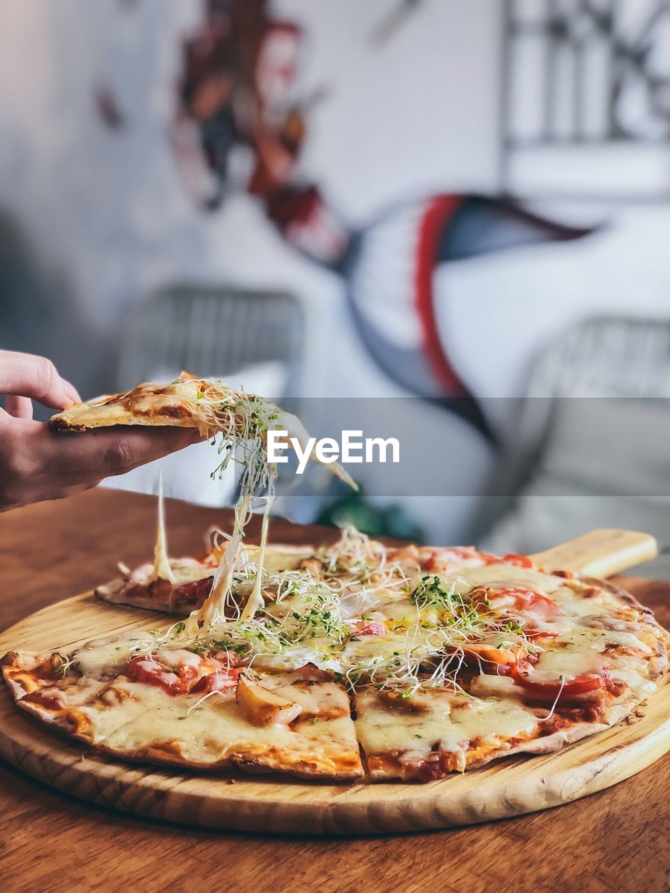 Cropped hand holding pizza at table