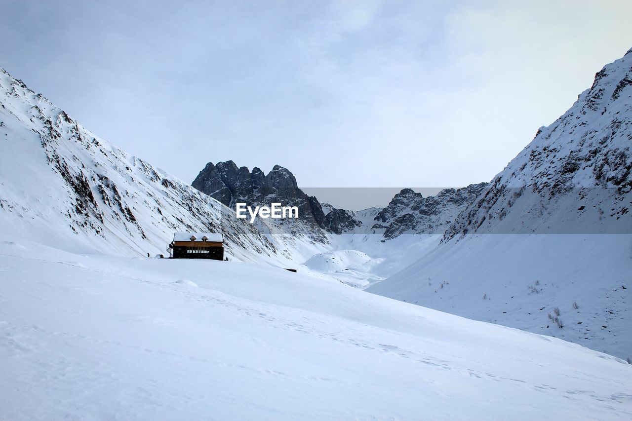 Built structure on snowcapped mountains against sky