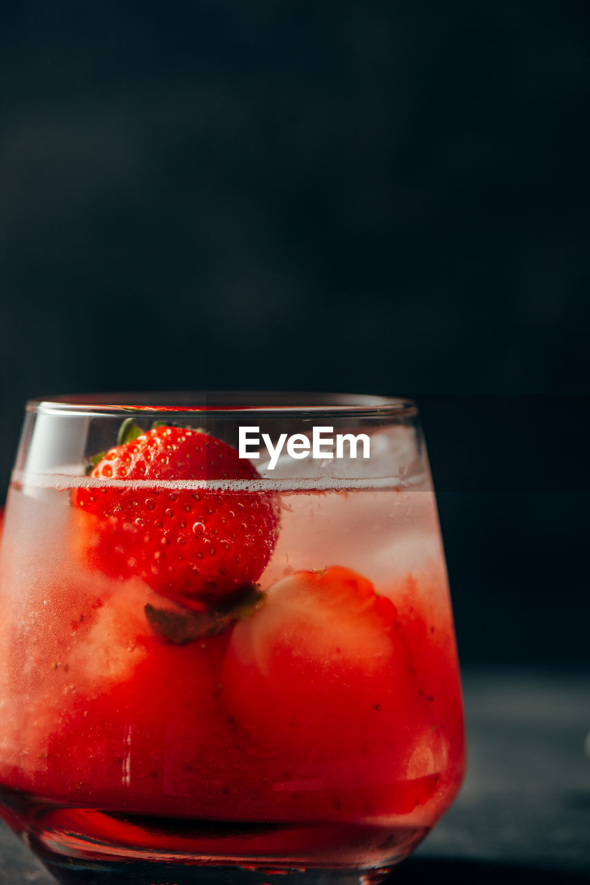 Delicious strawberry cocktail  with natural strawberry and ice cubes on grunge dark background.