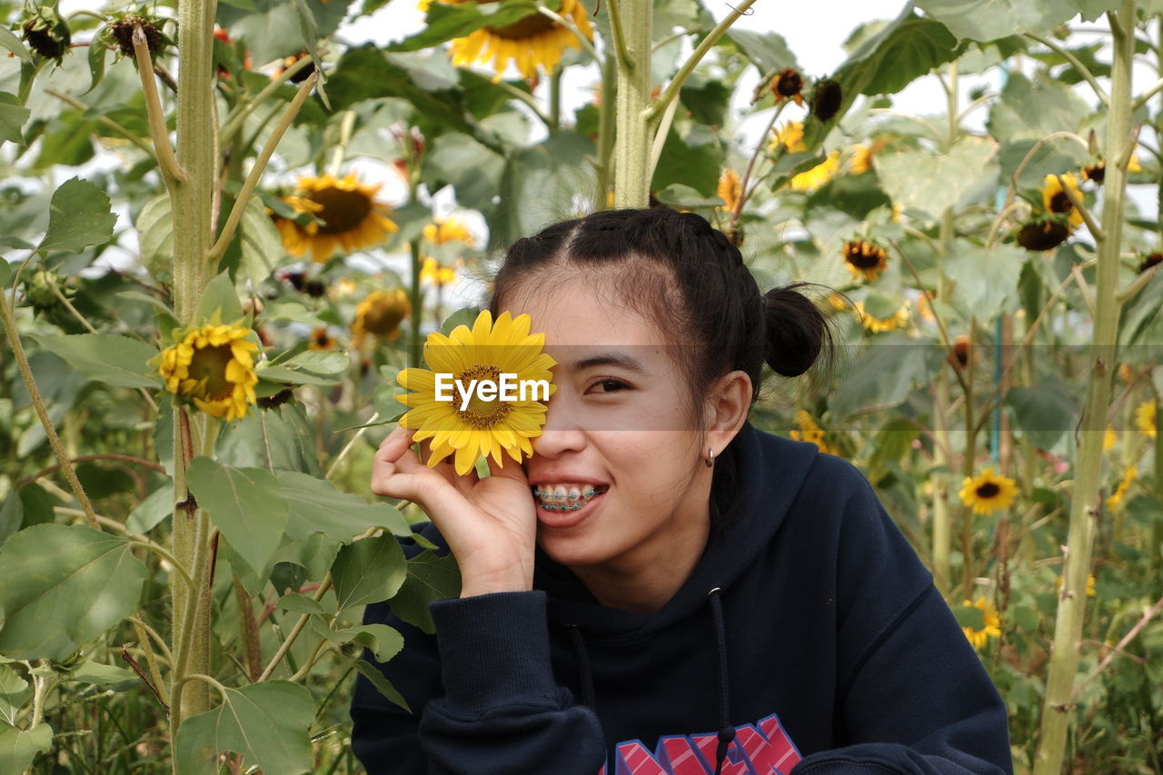 Portrait of smiling woman with yellow flower