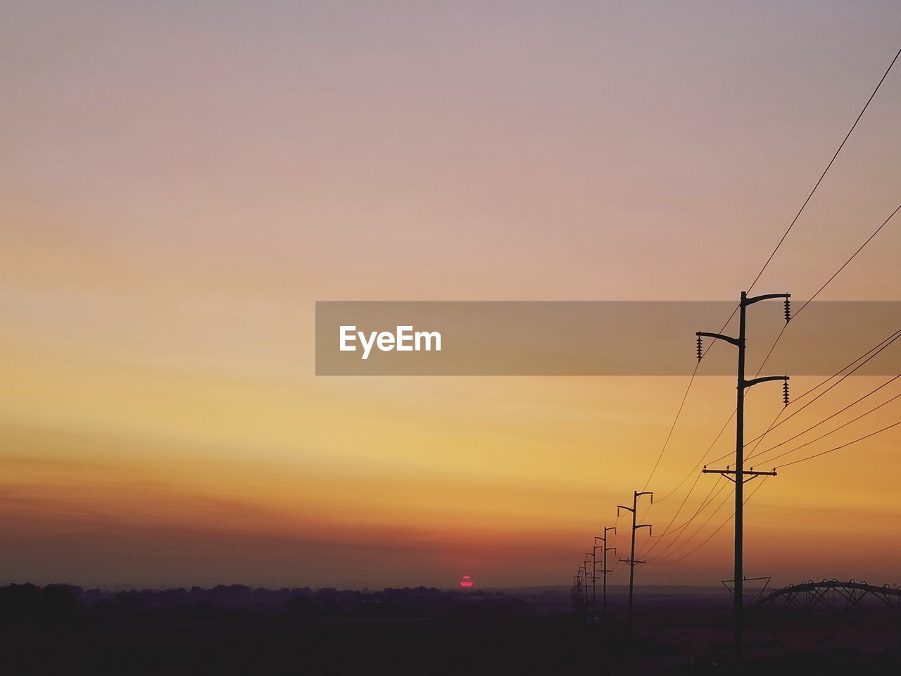 Silhouette electricity pylon against romantic sky at sunset