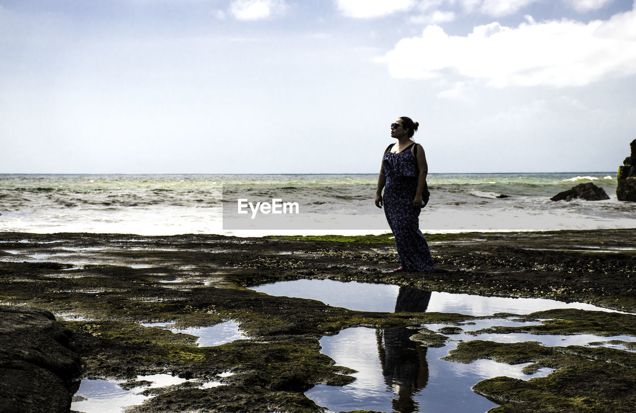 WOMAN STANDING ON BEACH