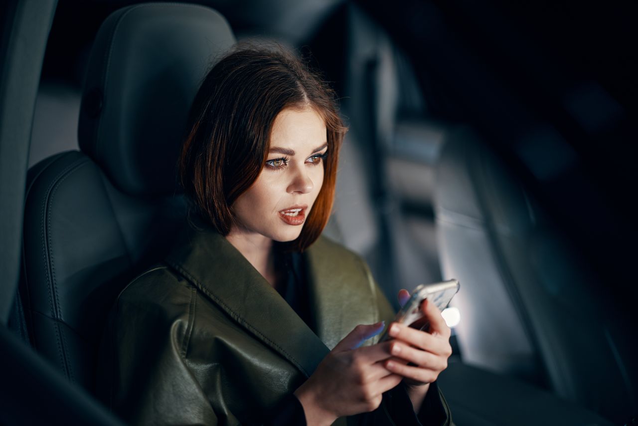 portrait of young woman using mobile phone while sitting in car