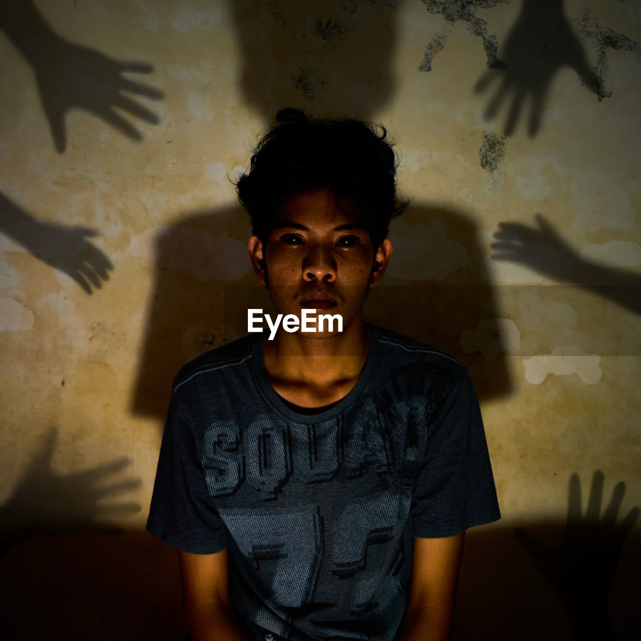 Portrait of young man standing against wall at home