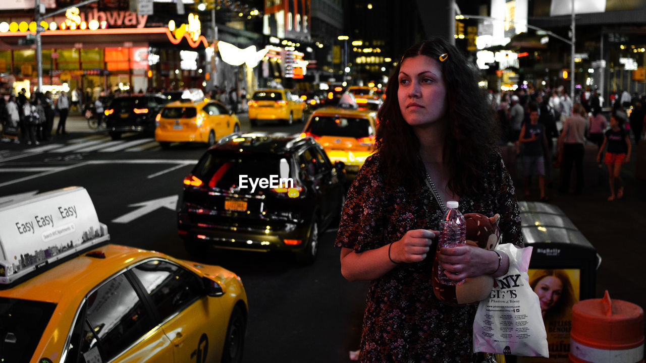 PORTRAIT OF YOUNG WOMAN STANDING ON CITY STREET