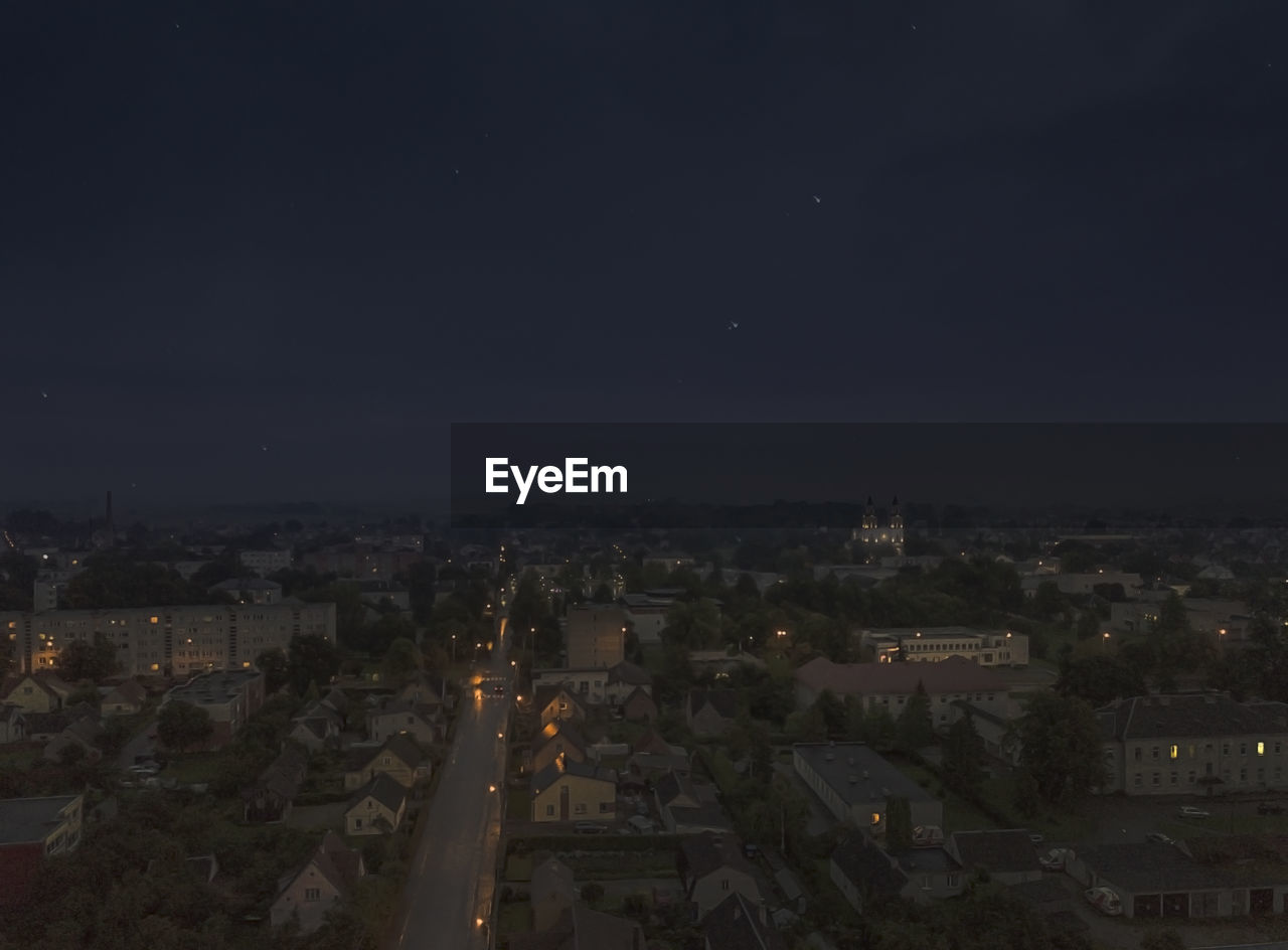 HIGH ANGLE VIEW OF ILLUMINATED BUILDINGS IN CITY AGAINST SKY