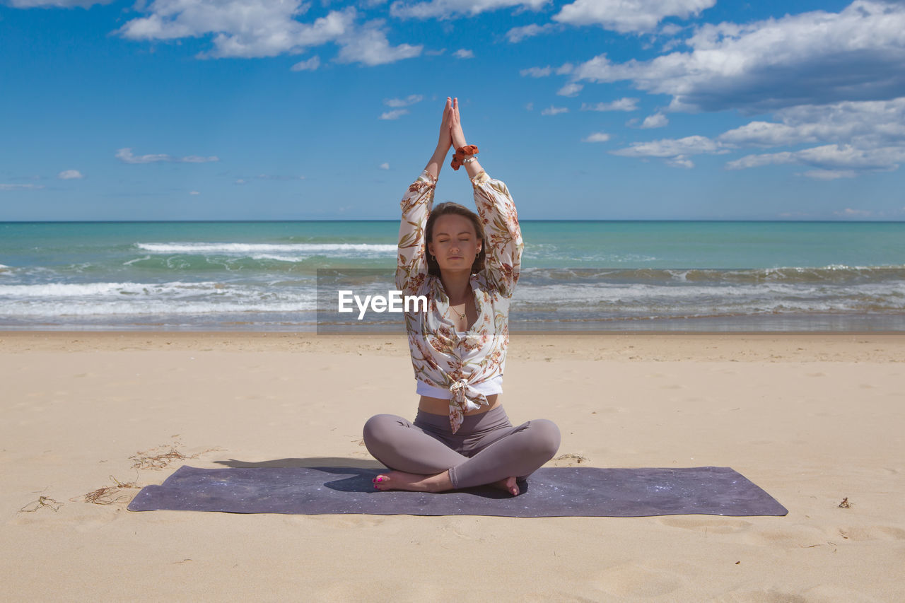 Beautiful young blonde doing pilate, yoga on the beach