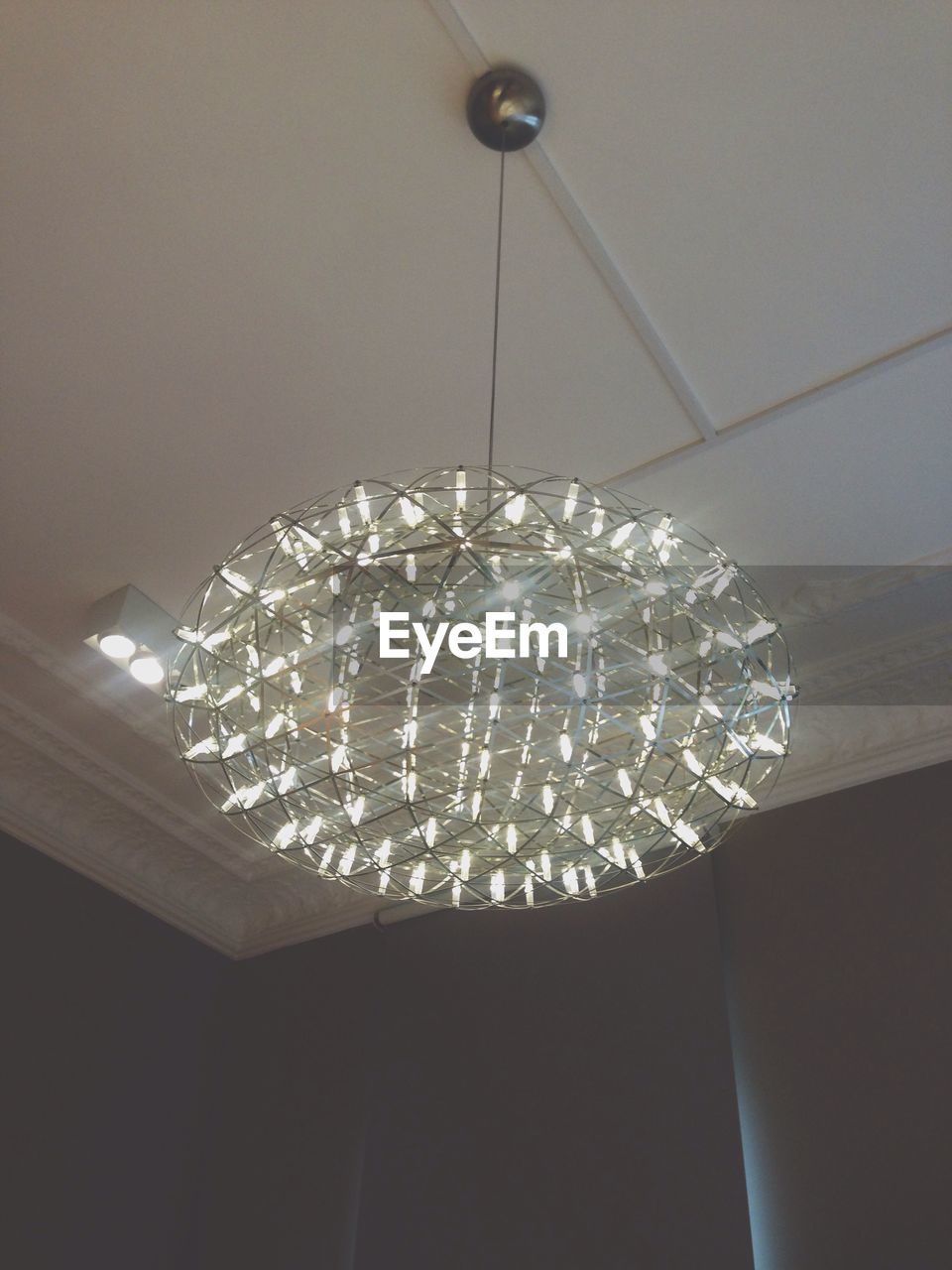 Low angle view of illuminated chandelier hanging on ceiling