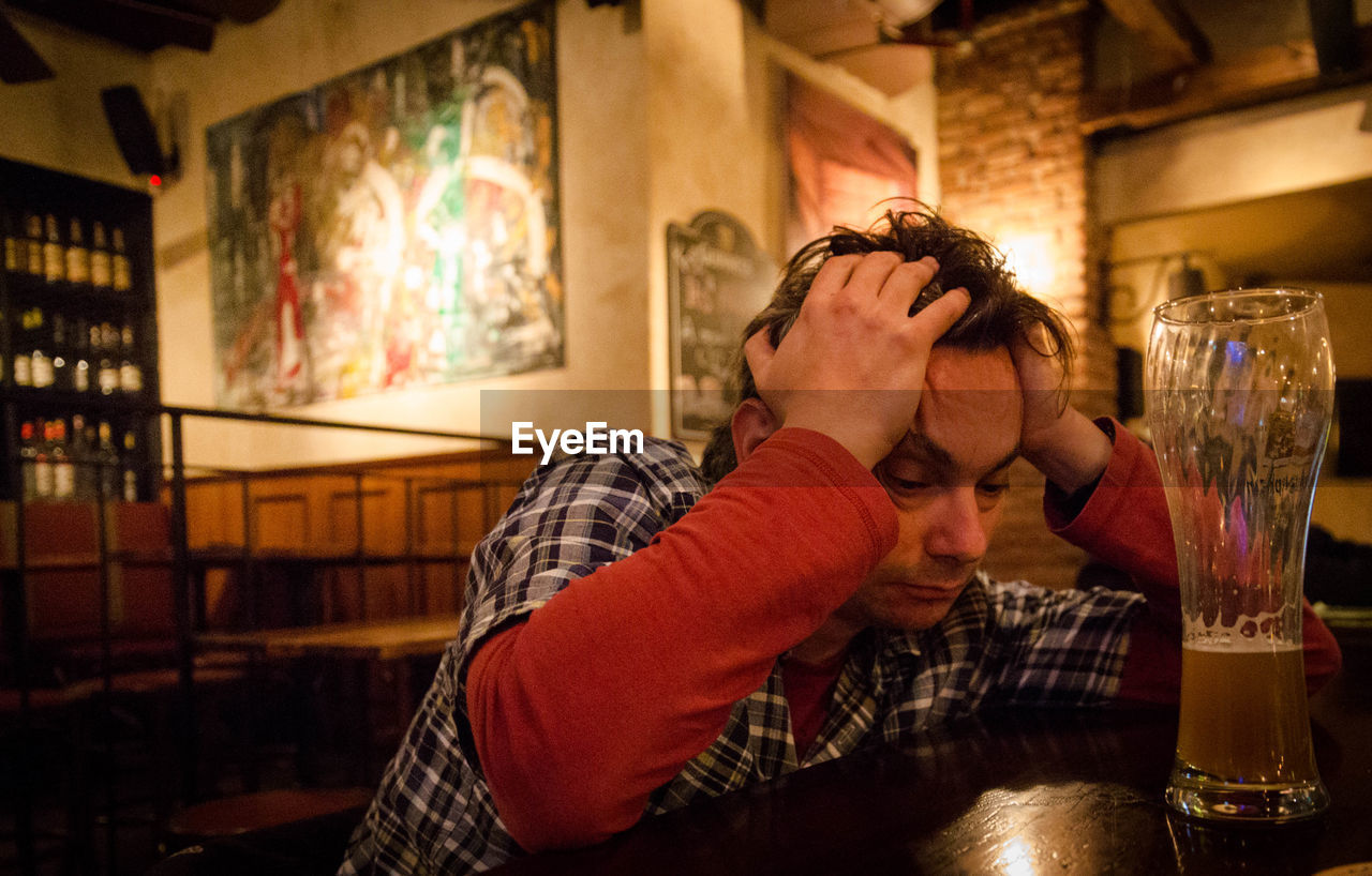 Drunk man sitting at table in bar