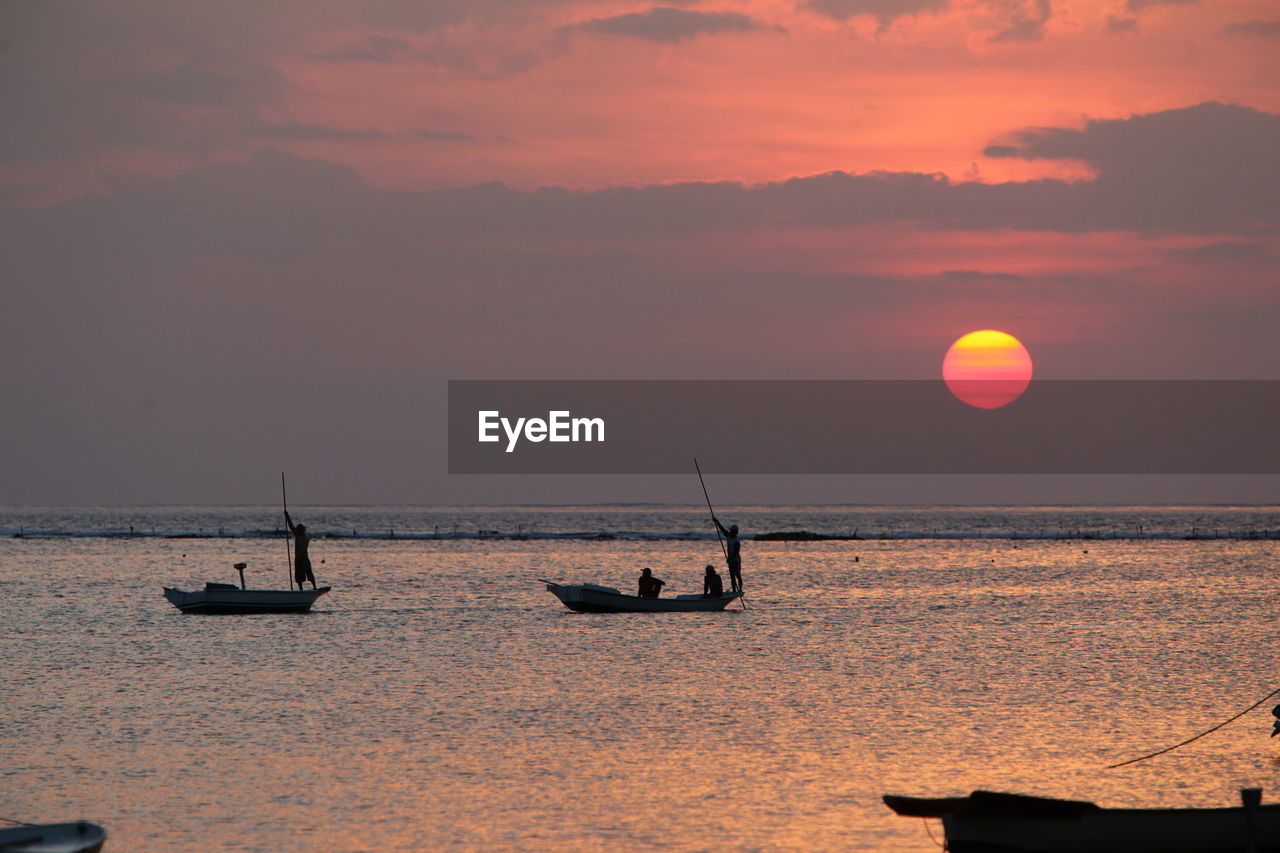 Silhouette people on boat in sea against cloudy sky during sunset