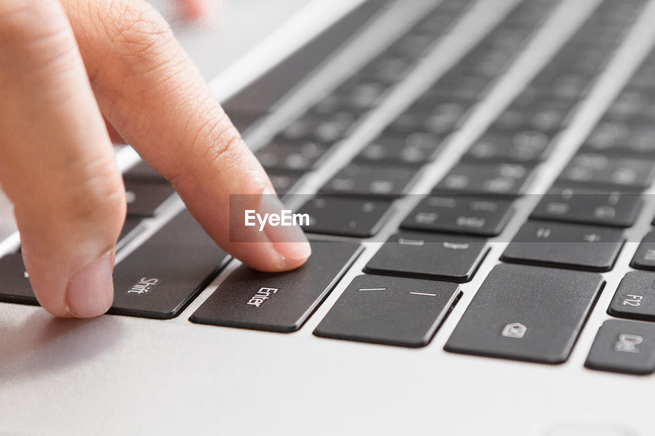 cropped hand using laptop keyboard