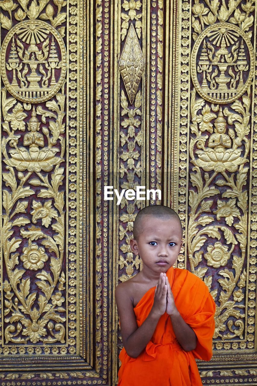 Portrait of boy in traditional clothing gesturing while standing against wall