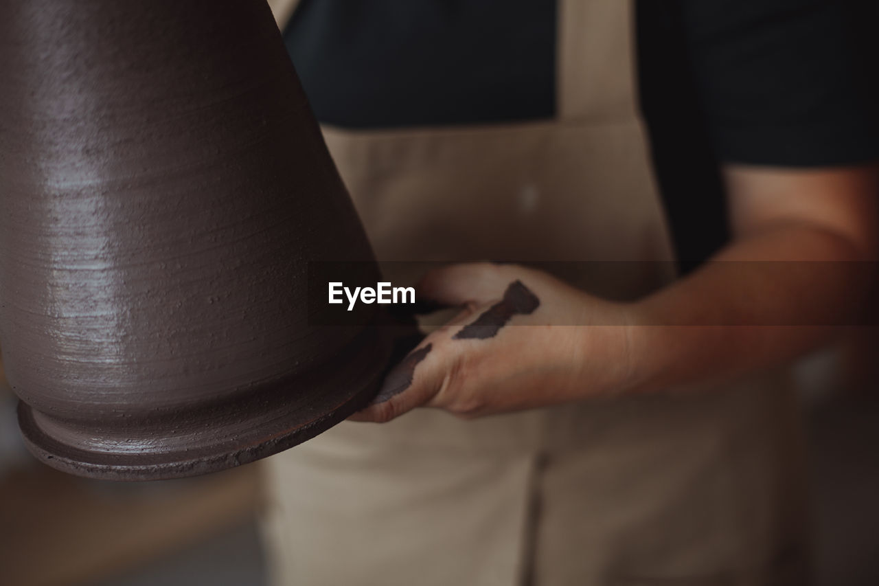 A middle-aged woman makes a vase of clay