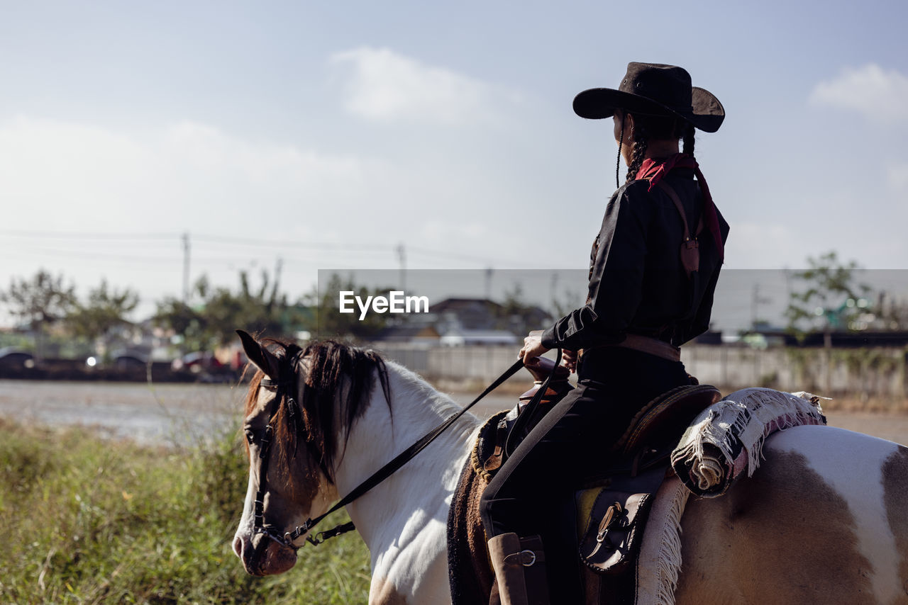 Cowgirl horseback riding, woman on horse at sunset