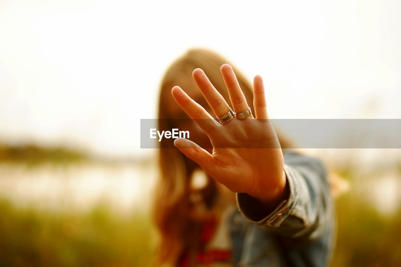 Woman showing stop gesture while standing against clear sky