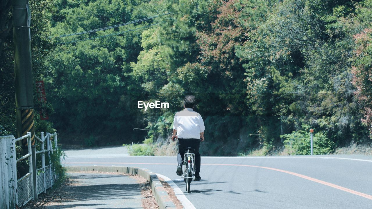 REAR VIEW OF PERSON RIDING BICYCLE