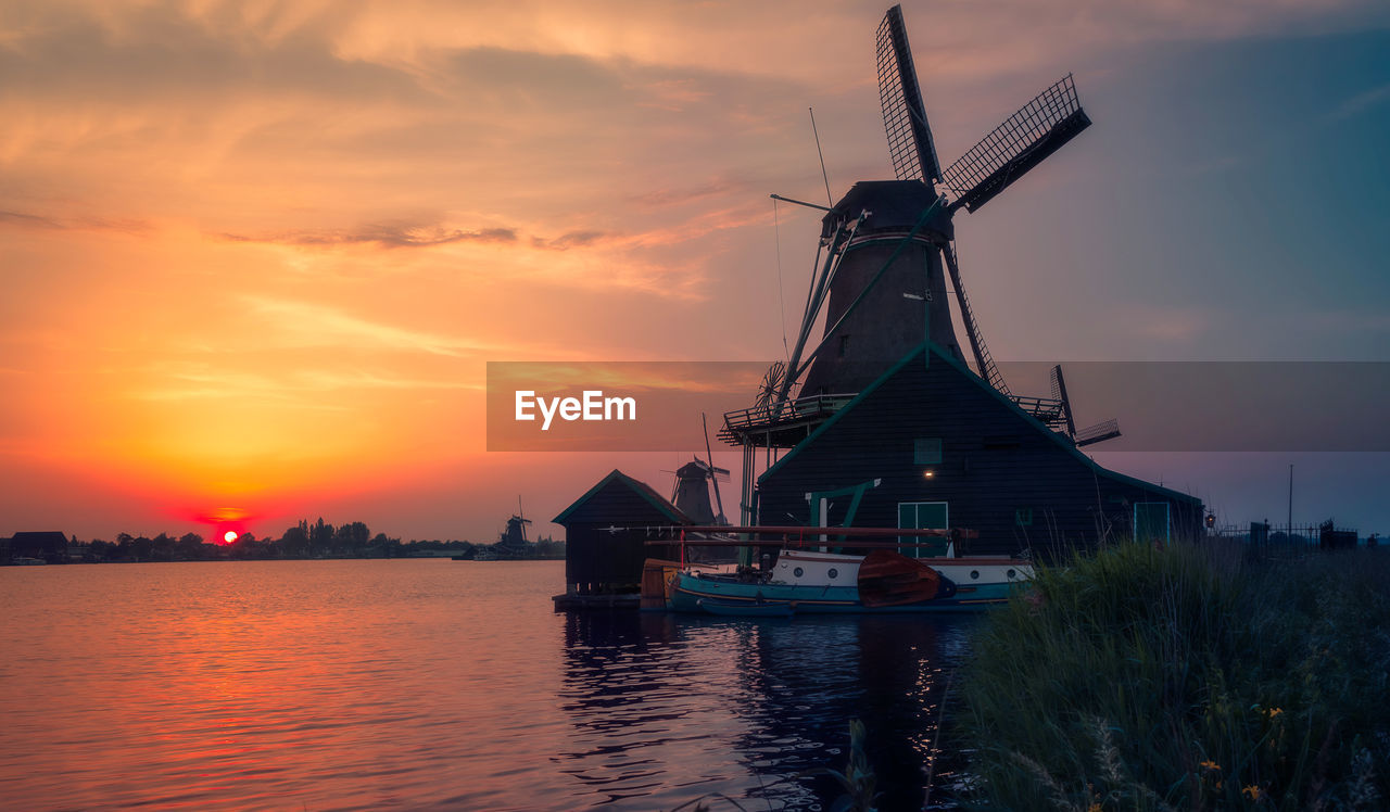 TRADITIONAL WINDMILL ON WATER AGAINST ORANGE SKY