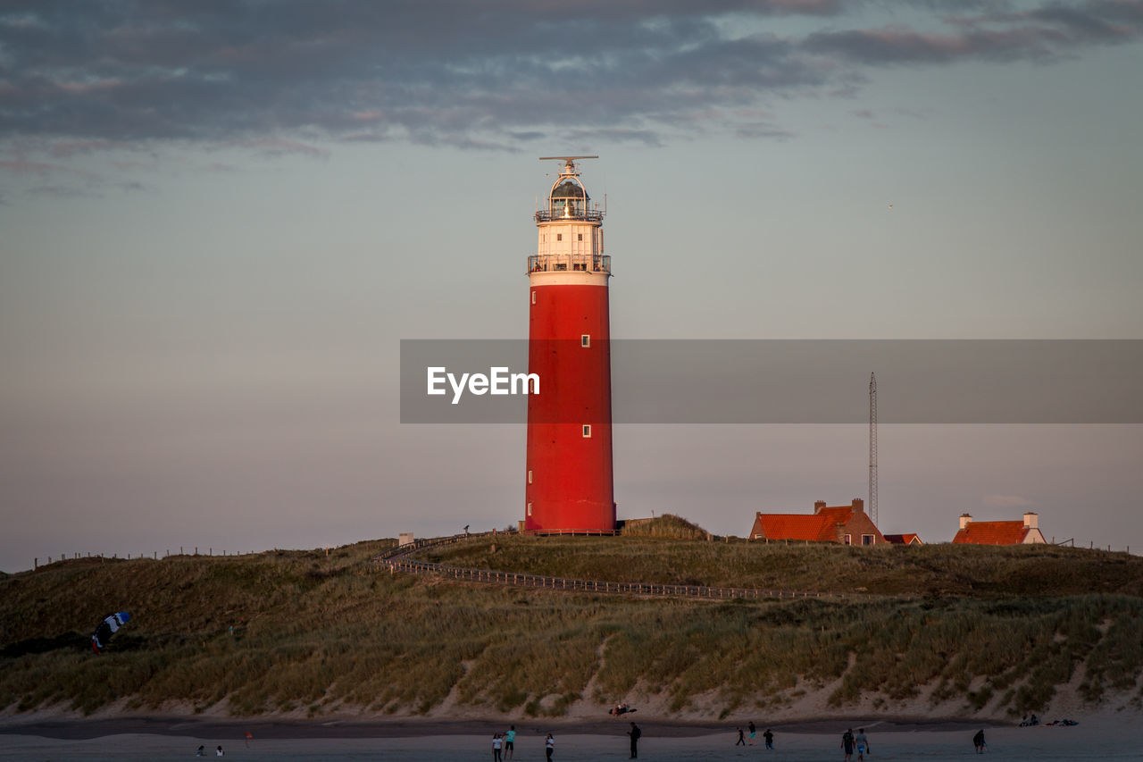Lighthouse on beach against sky during sunset