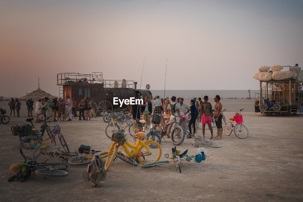 beach, group of people, bicycle, large group of people, crowd, sky, transportation, vehicle, men, nature, architecture, land, adult, sea, city, sunset, lifestyles, travel, sand, mode of transportation, water, sports, person, leisure activity, women, outdoors