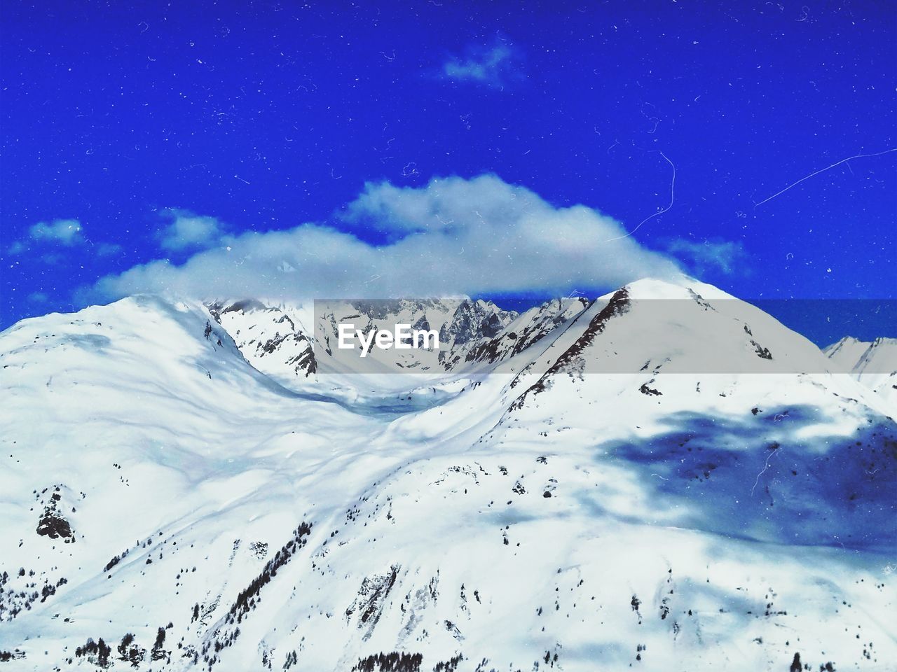 Scenic view of snowcapped mountains against blue sky