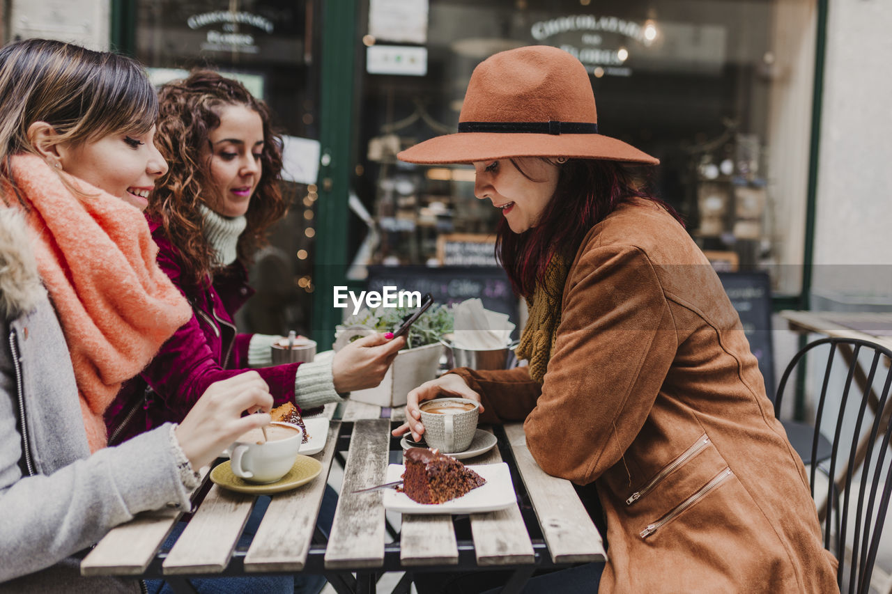 YOUNG WOMAN DRINKING GLASSES ON TABLE AT CAFE