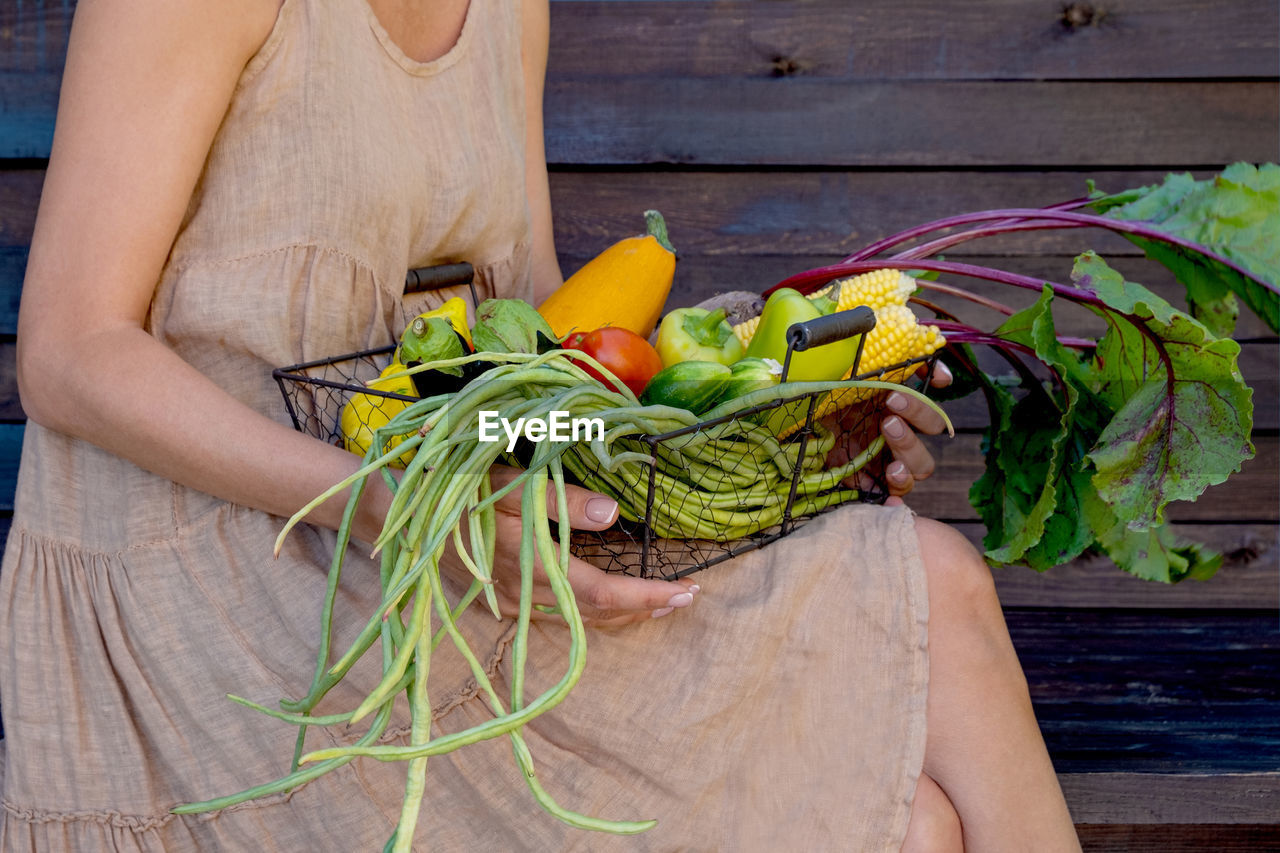 Eco-friendly concept with organic farm vegetables in the hands of a girl in a linen dress